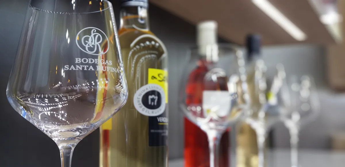 Copa grabada con el logo de Bodegas Santa Rufina junto a botellas de la bodega