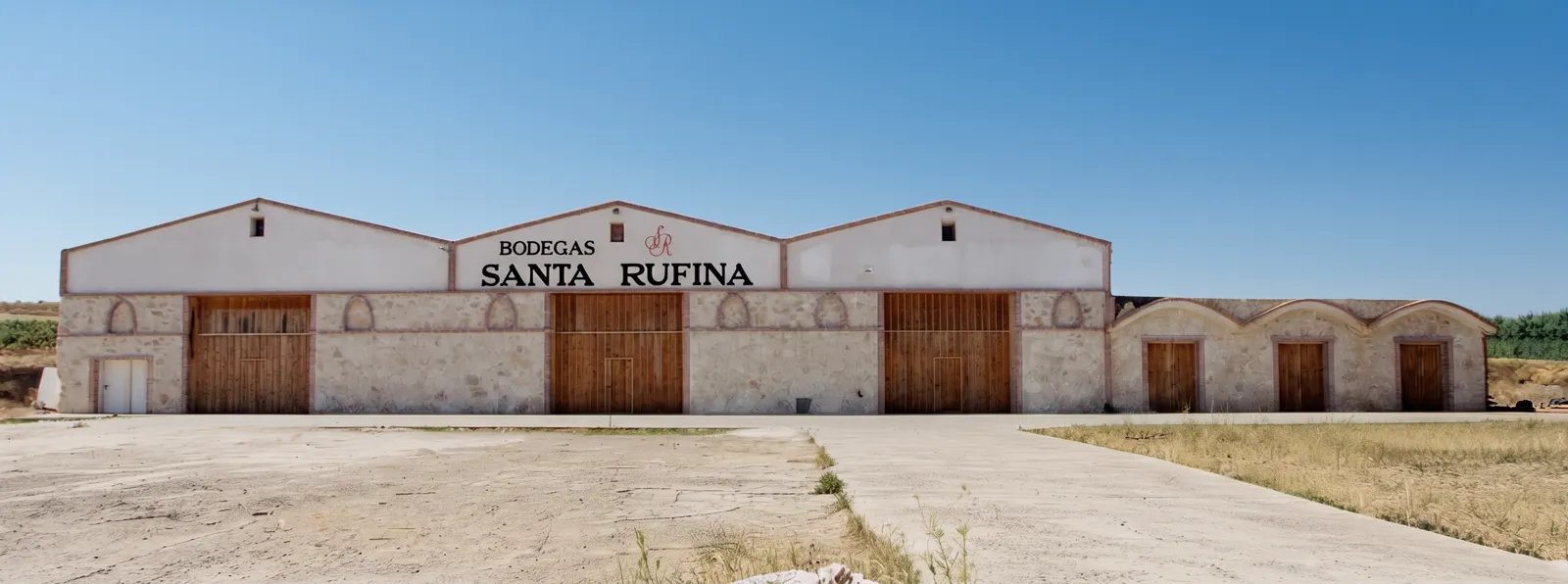 Fachada de Bodegas Santa Rufina en Cubillas de Santa Marta, con el nombre pintado sobre las tres naves